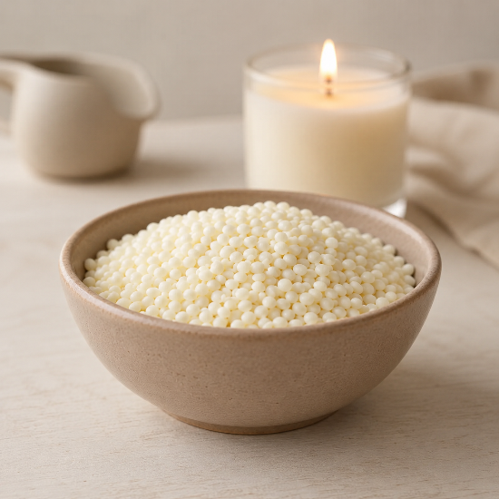 A beige ceramic bowl filled with wax beads, set on a light wooden surface with a lit cream candle and neutral home decor in the background.