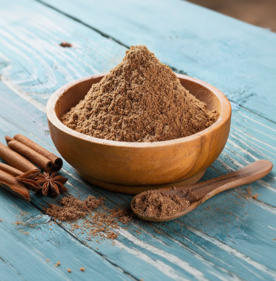 Wooden bowl filled with brown powder on a blue wooden surface with two chestnuts and a spoon.