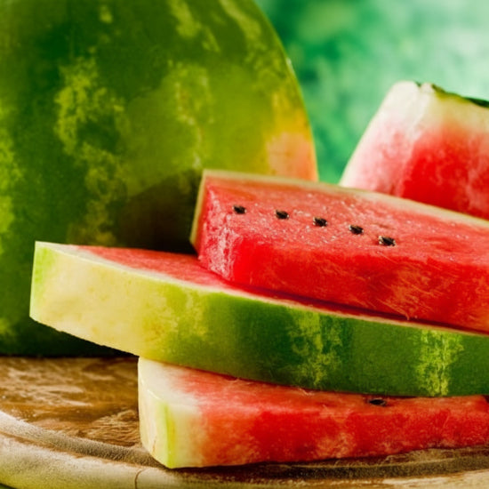 Sliced watermelon on a wooden cutting board with a blurred green background