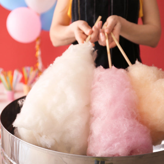 Cotton candy in various colors in a metal container with a person in the background.