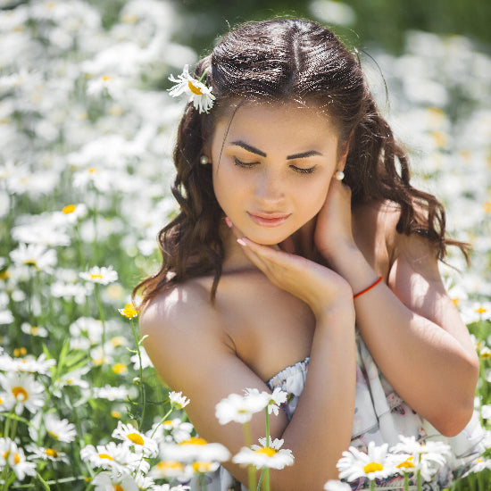 Woman in a field of white flowers with a daisy in her hair