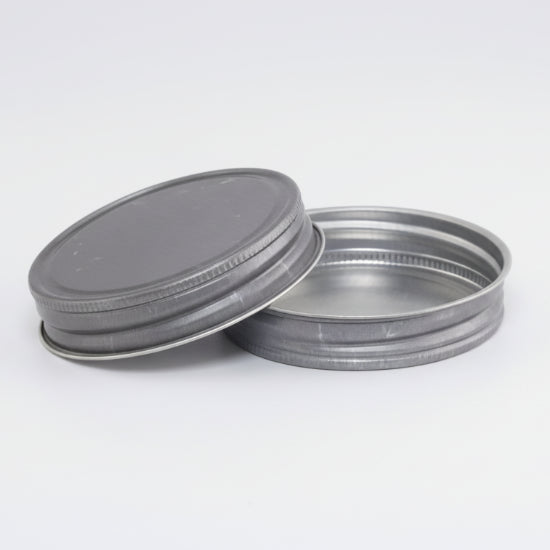 Two metal jar lids on a white background