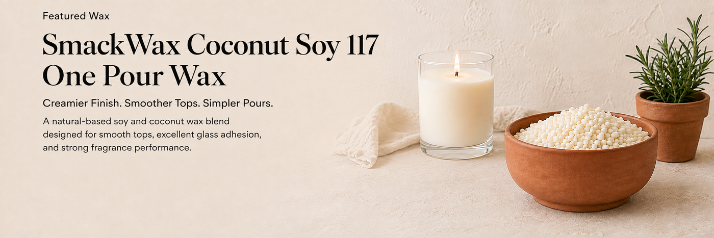 A candle in a clear glass jar with a lit wick sits on a light beige surface beside a bowl of white wax pears and a small potted plant. Text on the left reads 'Featured Wax SmackWax Coconut Soy 117 One Pour Wax' with a creamier finish and smoother tops description.