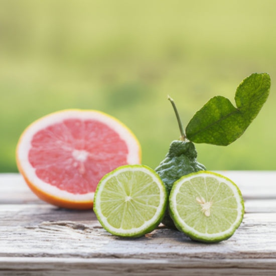 Sliced grapefruit and limes on a wooden surface with a blurred green background