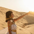 Woman in a desert setting with sand dunes and sunlit background