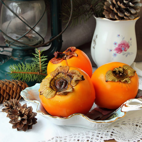 Fruits on a decorative plate with pine cones and a lantern in the background