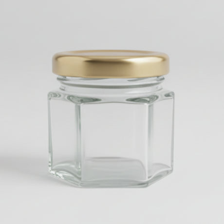 Small hexagonal glass jar with a gold lid on a black background