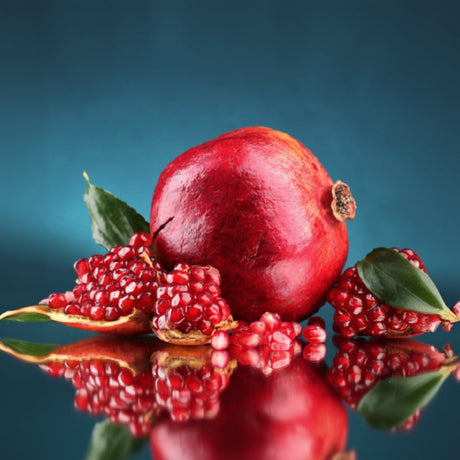 Pomegranate with seeds on a reflective surface against a blue background