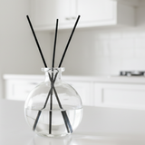 Clear glass diffuser with black sticks on a white surface