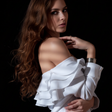 Woman wearing a white off-shoulder top against a black background