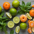 a selection of Limes, basil and mandarin oranges arranged on a greyish blue wooden table. bird's eye view