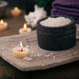 Candlelit scene with a bowl of salt and other items on a wooden surface