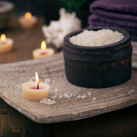 Candlelit scene with a bowl of salt and other items on a wooden surface