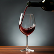Red wine being poured into a glass with a dark background