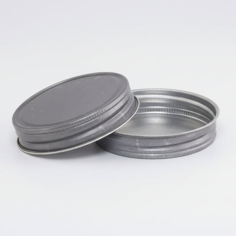 Two metal jar lids on a white background