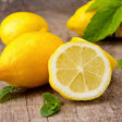 Fresh lemons with one cut in half on a wooden surface