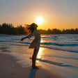 young woman, arms outstretched enjoying tropical breeze at the beach