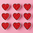 cinnamon red hots arranged to form solid hearts on a pink background. vibrant colors