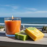 Candle and two soap bars on a wooden surface with a beach background