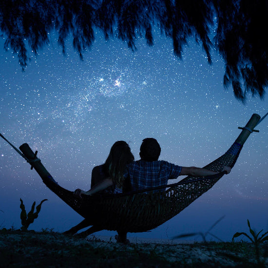 Two people in a hammock under a starry night sky.