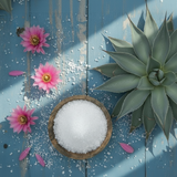 Bowl of white salt with pink flowers and a succulent on a blue wooden background