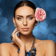 Woman wearing a blue floral necklace against a blurred blue background